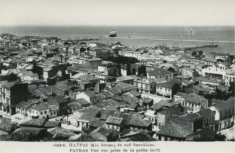 47. Άποψη της Πάτρας προς το λιμάνι. Στο κέντρο περίπου (τα μαύρα δέντρα) διακρίνεται η πλατεία Όλγας (φωτό από το Δασύλλιο), δεκαετία 1950.jpg