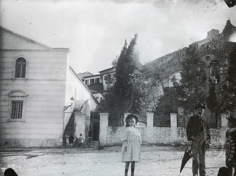 11. Ο ναός τού Αγίου Νικολάου με το παλιό καμπαναριό (στα δεξιά). Πίσω διακρίνονται σπίτια του Βλατερού και μέρος τού κάστρου. Η κόρη του φωτογράφου μπροστά στο ναό,  αρχές 20ου αι. (φωτό Αθαν. Ατζαρίτης).jpg