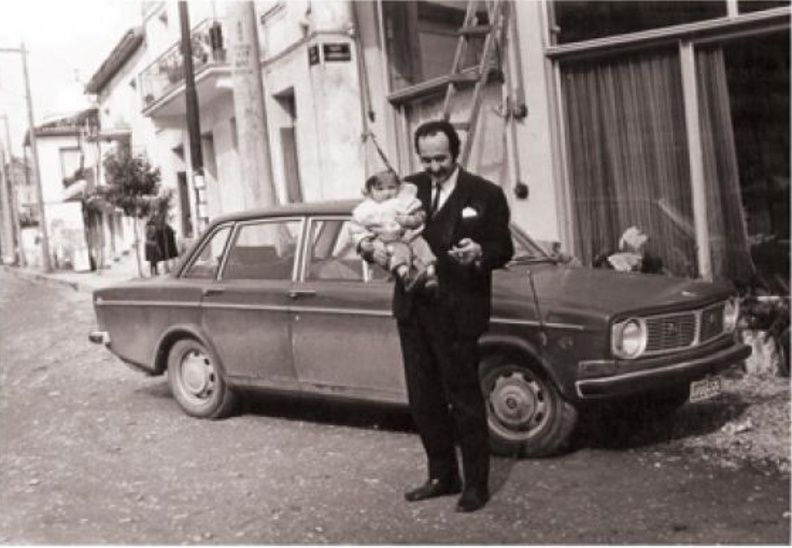 54. Ο Γεώργιος Καλλιμάνης με την κόρη του Μαρία έξω από το κατάστημα στην πλατεία Αχαϊκής Συμπολιτείας στο Αίγιο, 1972.jpg